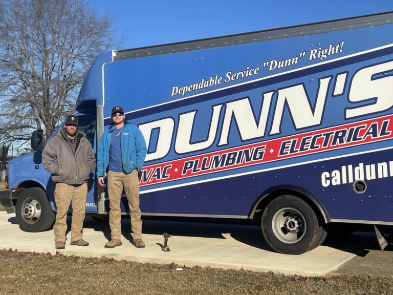 Two men in work attire stand in front of a Dunn's service truck in Calera, ready to provide expert HVAC, plumbing, and electrical services on a sunny day.