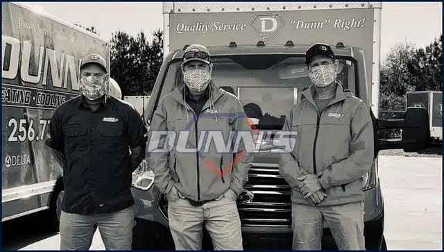 Three men wearing masks stand in front of a Dunn’s service van, posing for the camera. The van displays company branding and a slogan related to quality service.